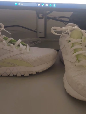 Vita Reebok sneakers med limegrön detalj - Storlek 38.5 men inlägg är 25 cm .Snygga vita sneakers från Reebok med mesh-ovandel och limegröna detaljer på sidan och plösen. Skorna har en sportig design med låg profil och grov sula som ger bra grepp. Perfekta för en aktiv vardag och streetstyle.