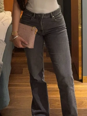 Grå jeans  - Säljer ett par snygga grå jeans med rak passform och hög midja. Jeansen har klassisk femficksdesign och bälteshällor. 
