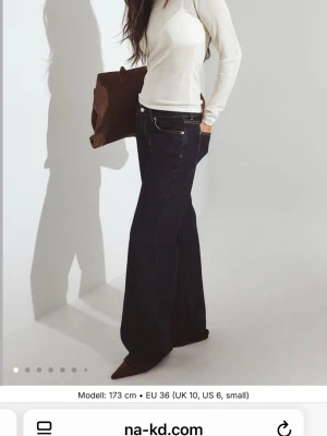 Mörkblå wide leg jeans från NA-KD - Snygga mörkblå jeans från NA-KD med wide leg-passform och hög midja. Klassisk femficksmodell med kontrastsömmar och raka, vida ben. Perfekta för en trendig och avslappnad look. Tillverkade i denim. Det finns slitningar längst ner på byxorna!!!