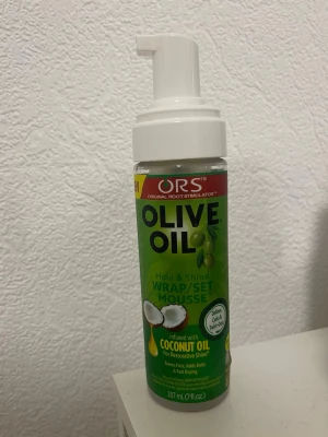 ORS Olive Oil Wrap/Set Mousse - Stylingmousse från ORS med olivolja och kokosolja som ger glans och stadga till håret. Perfekt för att forma och sätta frisyrer. Kommer i en grön plastflaska med vit pump och rymmer 207 ml.