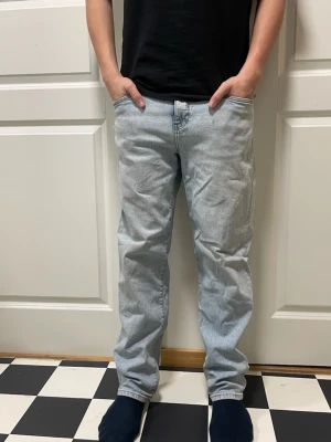 Ljusblå raka jeans i klassisk modell - Säljer ett par ljusblå jeans med rak passform och klassisk femficksdesign. Jeansen har hög midja och är tillverkade i bomull med en typisk jeansstruktur. Perfekta för en avslappnad och stilren look.