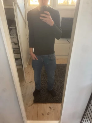 Mörkgrå tröja från Uniqlo - Säljer en stilren mörkgrå tröja från Uniqlo med rund halsringning och långa ärmar. Tröjan är tunnstickad och passar perfekt till lager-på-lager. Enkel design utan tryck eller mönster, vilket gör den lätt att matcha med olika outfits.