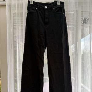 Svarta wide byxor från Divided - Säljer ett par svarta byxor från Divided i storlek 38. De har hög midja och vida ben för en chill och trendig look. Klassisk femficksmodell med knapp och dragkedja framtill. Perfekta till sneakers eller boots.
