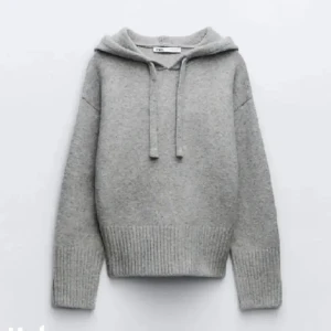 Grå stickad hoodie från Zara - Mysig grå stickad hoodie från Zara med huva och snörning. Tröjan har ribbade muddar och nederkant, samt lång ärm. Perfekt för lager-på-lager och chill dagar. Enkel och stilren design som funkar till det mesta.