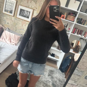 Mörkgrå Kashmir tröja - Mysig mörkgrå Kashmir tröja med rund hals och långa ärmar. Tröjan har en enkel och klassisk design som passar perfekt till jeans eller kjol. Den är mjuk och skön, perfekt för kyligare dagar.