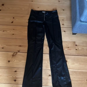 Svarta skinnbyxor från Gina Tricot - Snygga svarta skinnbyxor från Gina Tricot i bootcut-modell med låg midja men på mig är de lite högre upp. Säljer då de tyvärr var för stora för mig när jag fick hem dem. Köpta här på Plick och de är i storlek 164🥰