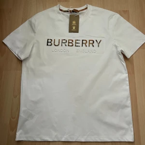 Vit Burberry t-shirt  - Vit t-shirt från Burberry med klassisk rund hals och korta ärmar.Perfekt för dig som gillar stilrena designer.pris kan diskuteras!!! S passar även M!!