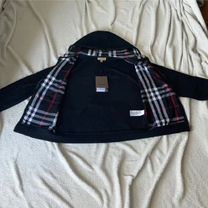 Svart rutig hoodiejacka från Burberry - Tjena säljer nu min Burberry hoodie, den är i nyskick har använt den nårga gånger men kände att den inte va min stil. Därför säljer jag den. Här är lite info om hoodien det är en. Svart hoodiejacka från Burberry med klassiskt rutigt foder i svart, vitt och rött. Jackan har broderad logga på bröstet och är tillverkad i 100% bomull. Perfekt för dig som vill ha en stilren och ikonisk look med streetvibe.
