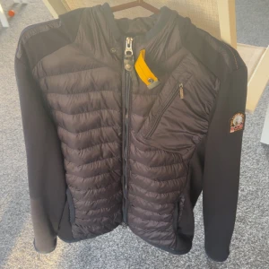 Svart pufferjacka från Parajumpers L - Säljer en svart pufferjacka från Parajumpers i storlek L. Jackan har quiltade partier framtill och baktill, mjuka ärmar och axlar i fleece, samt dragkedja och bröstficka. Klassisk PJS-logga på ärmen och snygg gul detalj vid halsen. 🟥🟥🟥HÖJER INOM SNAR FRAMTID PRISET! VA SNABBA 🟥🟥🟥