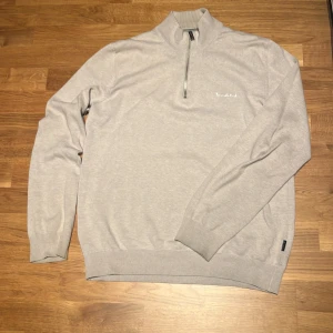 Beige half zip tröja Bondelid S - Snygg tröja från Bondelid med half zip och hög krage. Tröjan har lång ärm, ribbade muddar och diskret broderad logga på bröstet. Perfekt för lager-på-lager och chill stil. Tillverkad i mjuk bomullsmix.