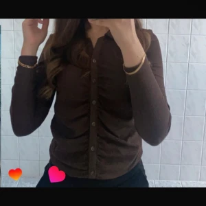Brun ribbad skjorta med knappar - Snygg brun skjorta från Cubus i storlek S. Skjortan är ribbad, har långa ärmar och knappar hela vägen framtill. Perfekt att styla med jeans eller kjol för en chill look.