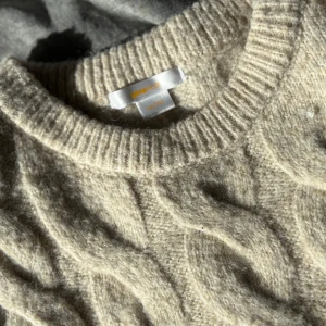 Beige stickad tröja från Gina Tricot - Supermysig beige stickad tröja från Gina Tricot med korta ärmar och grovt flätmönster. Tröjan har rund halsringning och ribbade muddar, perfekt för lager-på-lager och chill vibes.