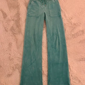 Mintgröna Juicy Couture byxor  - Supermjuka mintgröna byxor från Juicy Couture, stora fickor fram och bak samt snörning i midjan. Perfekta för en chill och trendig look. Klassisk logga broderad på ena fickan. 