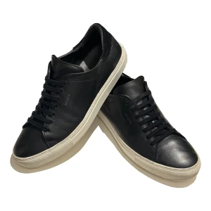 Riktigt fina Arigato sneakers - Stilrena svarta sneakers från Axel Arigato i skinn med vit platt sula. Klassisk låg modell med rund tå och svarta snören. Perfekta för dig som gillar minimalistisk och clean stil. St 46, hör av er om det är något ni undrar över