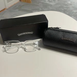 Transparenta glasögon från Chrome Hearts - Säljer ett par stilrena och unika glasögon från Chrome Hearts med transparent, rektangulär båge i plast. Snygga silvriga detaljer med blommönster på skalmarna. Kommer med svart fodral i skinn och originalförpackning.