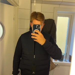 Mörkblå väst från Matinique  - Snygg mörkblå dunväst från Matinique i storlek L. Västen är otroligt stilren med quiltad design och dragkedja framtill. Perfekt att slänga över en hoodie eller tröja för en clean look. Färg: Dark Navy.  Köpte den för 1699 och den är sprillans ny och jag säljer den ändast för 1299 men pris kan eventuellt diskuteras