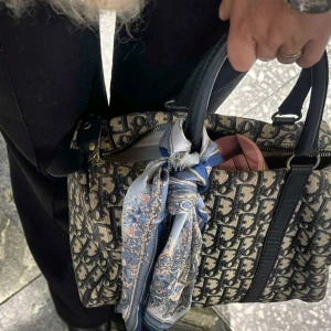 Aldrich Ave, Blommig blå och vit sidenscarf - Snygg sidenscarf med blommigt mönster i blått, vitt och grått. Scarfen har en kvadratisk form och kan stylas runt halsen eller på väskan. Detaljerade blommor och paisley-inspirerade inslag ger en lyxig och trendig vibe. Perfekt accessoar för att lyfta din outfit.