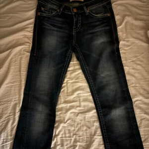 Mörkblå 1921 jeans straight fit - Säljer ett par mörkblå 1921 jeans med snyggt slitna detaljer och klassisk femficksdesign. Jeansen har en rak passform och är tillverkade i mjukt denimtyg med lite stretch för extra komfort. Perfekta till sneakers eller boots.