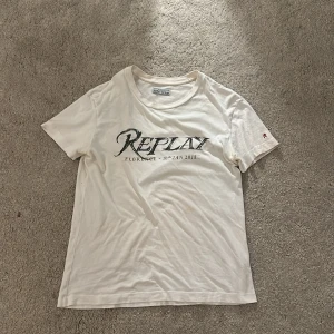 Vit Replay t-shirt med tryck - Vit t-shirt från Replay med coolt tryck på bröstet där det står 'Replay Florence - 10th Jan 2018' och texten 'Denim Revolution' på ryggen. Rund hals och korta ärmar, tillverkad i mjuk bomull. Liten röd Replay-logga på ena ärmen.
