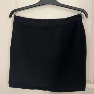 Svart stickad kortkjol - Enkel och stilren svart stickad kortkjol med bred ribbad midja.