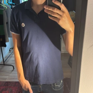 Mörkblå Moncler pikétröja - Hallå! Säljer nu en ursnygg moncler piké med en klassisk touch. Tröjan passar dig med storlek M och kanske S beroende på hur lång du är. Köpt på Nk i vintras och skicket är otroligt bra. Hör av er vid minsta tanke!!!!