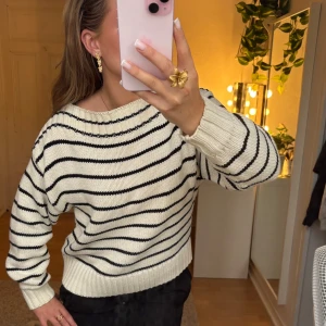Randig stickad tröja - En jättefin vit och svart stickad tröja. Tröjan är väldigt tjockt stickad viket gör den väldigt varm. Den är lite oversized i modellen. Den är lite creme vit med svarta ränder och passar till allt. Finns inga defekter på den alls och är knappt använd. Kolla i bio innan köp. Nypris 499