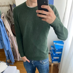 Mörkgrön stickad tröja Bondelid M - Mörkgrön stickad tröja från Bondelid i storlek M. Klassisk rund halsringning och ribbade muddar vid ärmslut och nederkant. Perfekt för lager-på-lager och chill stil. Enkel och stilren design som funkar till jeans eller chinos.