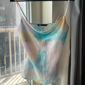 Pastellfärgad linnetopp från Zara - Säljer en superfin linnetopp från Zara i pastelliga färger med tie-dye känsla. Toppen har tunna axelband och en lös, flowy passform. Färgerna går i blått, gult, rosa och vitt. Storlek S. 