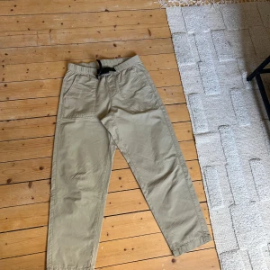 Beiga chinos från Levi's - Snygga beiga chinos från Levi's med elastisk midja och inbyggt bälte. Byxorna har raka ben, sidofickor och bakfickor med den klassiska Levi's-taggen. Perfekta för en chill och stilren look. Tillverkade i mjuk bomull för extra komfort.