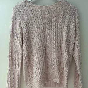 Ljusrosa kabelstickad tröja H&M - Superfin ljusrosa kabelstickad tröja från H&M i storlek M. Tröjan har klassiskt flätmönster framtill och på ärmarna, rund halsringning och ribbade muddar. Perfekt för lager-på-lager och chill höst- och vinterstil.