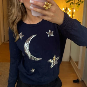 Mörkblå tröja med tryck från savannah - Mörkblå stickad tröja från Savannah med stora silvriga paljetter i form av måne och stjärnor på framsidan. Tröjan har rund halsringning och är i mjukt stickat material. Jätte fin tröja men igen så tycker jag det skär sig eftersom jag använde guldsmycken och därav att jag säljer den. I jätte fint skick. Storlek är ungefär xs-m jag har oftast S och den sitter bra på mig. Läs bio innan köp☺️pris pga märke, bra skick, fin