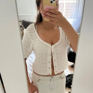 Kortärmad kofta - Supersöt vit kortärmad kofta   från Amisu med. Den är croppad och har fina pärlknappar framtill. Luftigt virkat mönster och vågig kant nertill. Har lite fläckar på insidan som inte syns(bild 3)