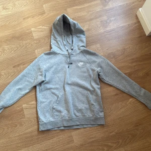 Grå hoodie från Nike med huva/szara bluza z kapturem/kardigan - Säljer en klassisk grå hoodie från Nike i storlek S. Tröjan har huva med snörning, magficka och Nike-logga på bröstet. Perfekt för chill dagar eller när du vill ha en enkel och stilren look.