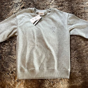 Ami Paris Sweatshirt Grå - Säljer en stilren grå sweatshirt från Ami Paris sweatshirt i storlek S. Skicket är gott som nytt 10/10🙌  och matrialet är gjort av bomull så den håller en varm Denna vinter och Höst🍁🍂❄️⛄️ Tagsen sitter kvar!! Och Tröjan är inte använd. ❗️Priset kan diskuteras ❗️Kontakta Mig vid Frågor och mer Bilder🤝