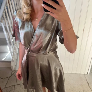  omlottklänning med v-ringning - Säljer en glansig grön klänning med v-ringning och korta ärmar. 