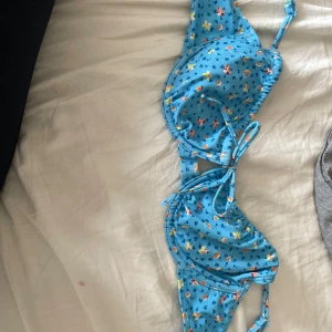 Blommig blå bikini från bikbok  - Supersöt blå bikini med små blommor i olika färger från bikbok. Bikinin har bygel, knyt framtill och axelband. Perfekt för stranden eller poolen, och den blommiga designen ger en riktigt somrig vibe.