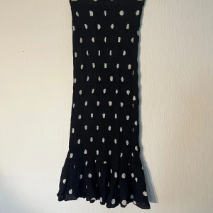 Svart prickig långkjol från Gina Tricot - Supersöt svart långkjol från Gina Tricot. Modellen har en volangkant längst ner. I storlek 32. Ny med prislapp. 