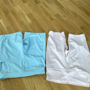 OTP och NA cykelshorts i pastell - Två par cykelshorts, ett ljusblått från OTP och ett ljusrosa från NA. Båda är midwaist och har en tight passform med släta sömmar. Materialet är syntet, perfekt för träning. Det blåa paret har en praktisk ficka på sidan. Snygga och bekväma för aktiva dagar. (80kr för båda)