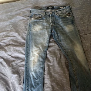 Replay ljusblå jeans, storlek 30 - Säljer ett par ljusblå jeans från Replay i klassisk femficksmodell. Jeansen har slitna detaljer, snygg tvätt och läderpatch bak i midjan. Materialet är jeans och passformen är normal med raka ben. Perfekta för dig som gillar en avslappnad och trendig look.