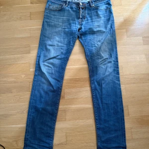 Jacob Cohen limited edition - Snygga blå jeans från Jacob Cohen, limited edition nr 130 av 156. Klassisk femficksmodell med orangea detaljer och patch bak. Jeansen har raka ben och är tillverkade i mjukt denimtyg med japanska tyger och handgjorda detaljer.