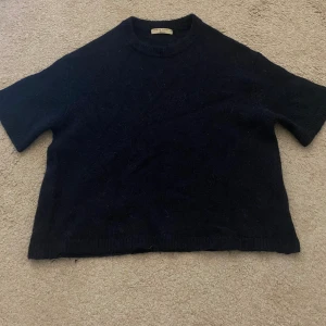 Mörkblå stickad tröja Gina Tricot - En mörkblå stickad tröja från Gina Tricot med rund hals och trekvarts ärmar. Tröjan är i ett mjukt och mysigt material som passar perfekt till lager-på-lager. Enkel och stilren design som funkar till många outfits.