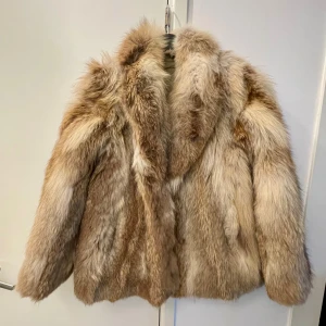 Beige pälsjacka med fluffig look - *Superfluffig pälsjacka i beige och bruna toner, perfekt för dig som vill sticka ut.                                              Jackan har bred krage och lång ärm, med en riktigt lyxig känsla.                                                                   Fodrad insida för extra komfort och värme.               Snygg till både jeans och kjol .