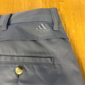 Adidas golfshorts strl 30 - Golfshorts i en snygg gråblå ton.