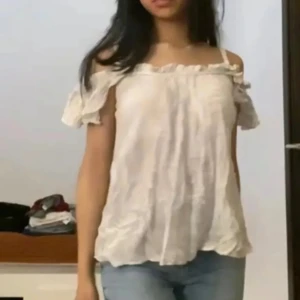 Beige offshoulder blus - Supersöt beige blus från Gina Tricot i storlek 34. Offshoulder-modell med volangdetaljer längs halsringningen och ärmarna. Tunt, luftigt tyg med diskret struktur och lätt rynk. Perfekt för en fräsch och somrig look.