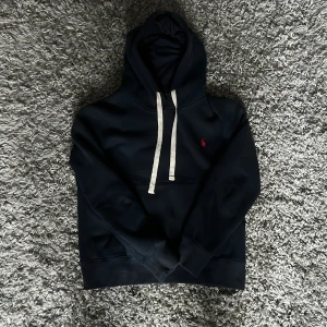 Marinblå hoodie från Ralph Lauren - Säljer nu min marinblåa ralph lauren hoodie då jag inte använder den längre, en lite defekt se sista bild därav priset. [Skick: 8/10] [Nypris:1999:-] [Mitt pris: 499] Hör av er vid frågor och funderingar. 