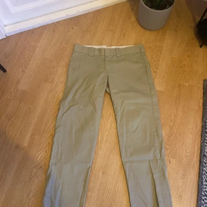 Beige Dickies Slim Straight chinos - Snygga beige chinos från Dickies i modellen Slim Straight. Byxorna har klassiska hällor för bälte, raka ben och en stilren look. Perfekta för dig som vill ha en clean och enkel stil med street-vibe. Materialet är slitstark bomull som känns bekvämt hela dagen.