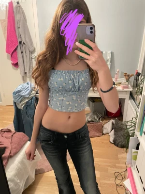Blå blommig croppad bandeau topp - Söt ljusblå bandeau topp med små vita blommor och croppad passform. Toppen har resår upptill och nedtill för en bekväm och snygg siluett. Perfekt till jeans eller kjol för en fräsch sommarlook.