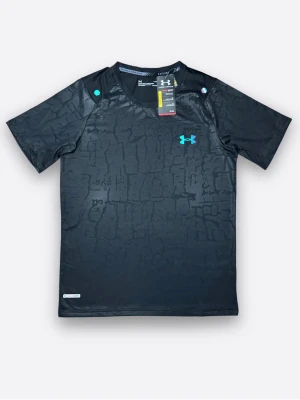 Svart tränings-tshirt från Under Armour. Finns i alla storlekar! - Svart tränings-tshirt från Under Armour med penslat mönster och turkos logga på bröstet. Tillverkad i lätt och ventilerande syntetmaterial, perfekt för intensiva träningspass. Kort ärm och rund hals för maximal rörelsefrihet.