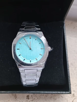 Silverklocka med "Tiffany Blue" Urtavla - Säljer en otroligt snygg klocka i silver med en ljusblå/turkos urtavla. Färgen poppar verkligen och ger en fräsch, exklusiv känsla.                                  Skick: Helt ny, oanvänd och kommer i box.          En perfekt accessoar för att lyfta din outfit,