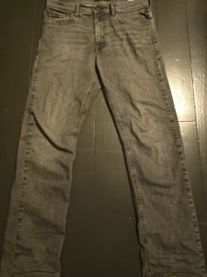 Replay grå jeans straight fit - Säljer ett par grå jeans från Replay med klassisk femficksdesign och raka ben. Jeansen har snygga detaljer på bakfickorna och Replay-logga vid myntfickan. Tillverkade i slitstarkt bomullsmaterial och har en neutral tvätt som passar till det mesta.